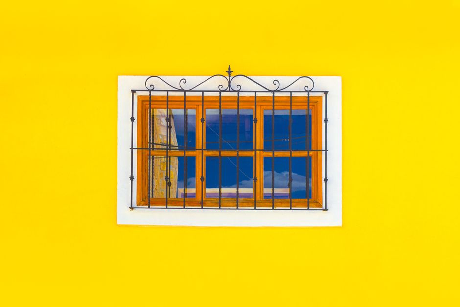 Small window with a wooden frame set in a yellow painted wall